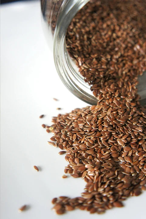 Flaxseeds spilling from a glass jar